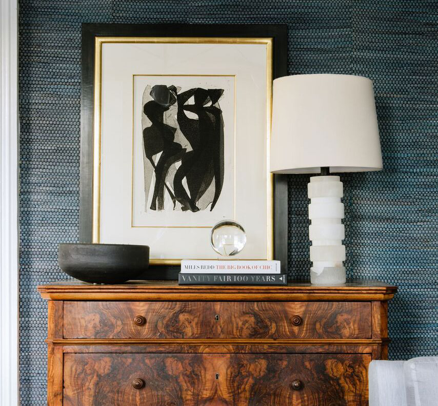 Framed abstract figure study and alabaster lamp on a burl wood chest