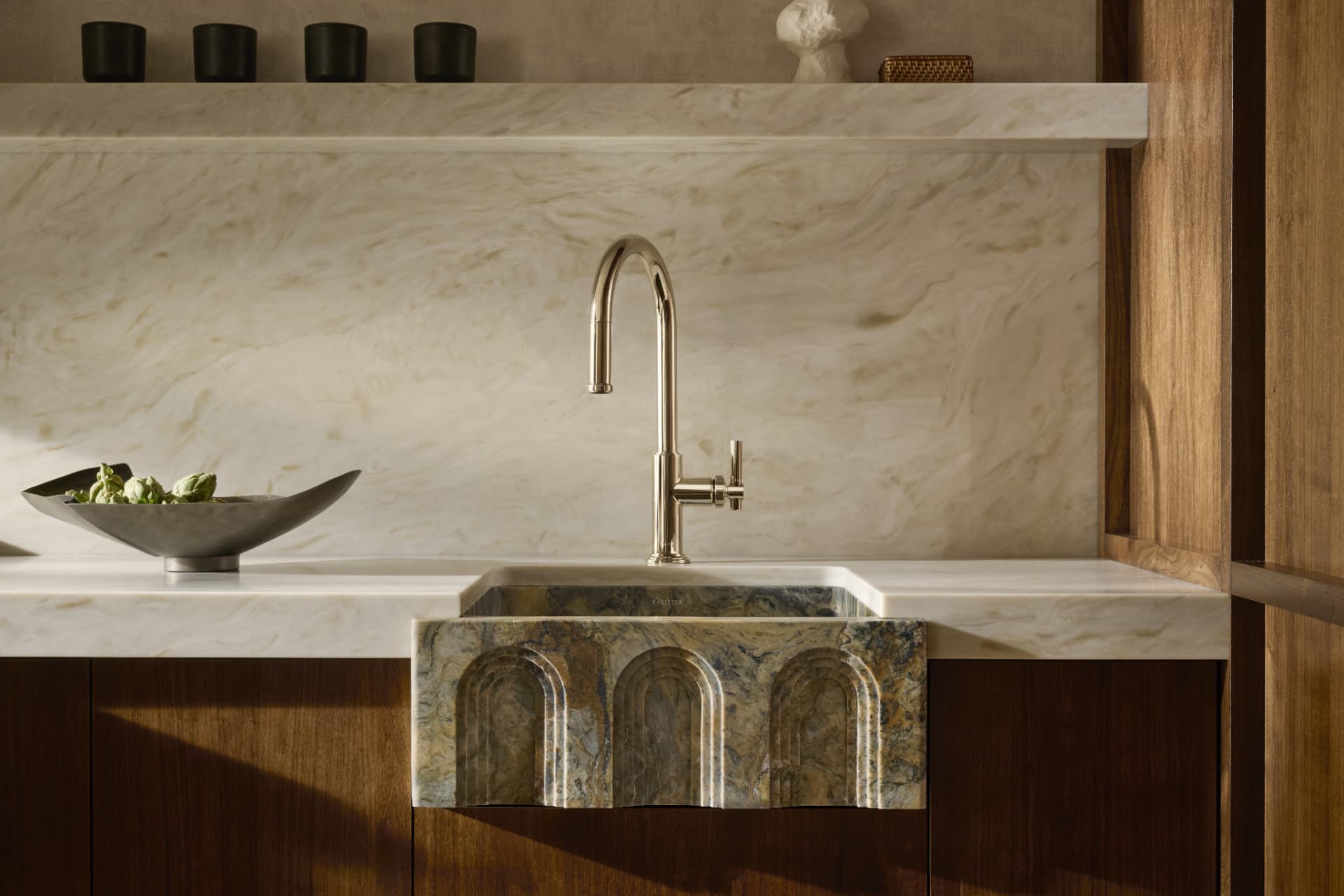 Marble kitchen counter with fluted stone apron sink and polished nickel gooseneck faucet